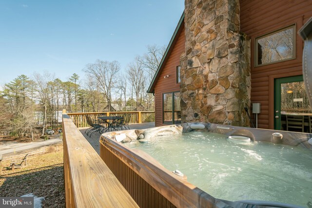 wooden deck featuring a hot tub and outdoor dining space