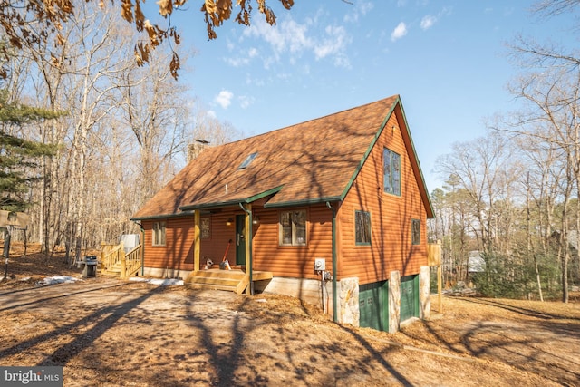 view of front of property with a shingled roof, a chimney, and log veneer siding