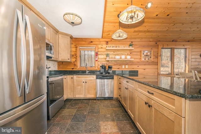 kitchen with light brown cabinetry, appliances with stainless steel finishes, stone finish flooring, a sink, and a peninsula