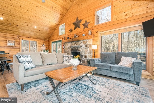 living room featuring high vaulted ceiling, a fireplace, wood finished floors, and wooden walls