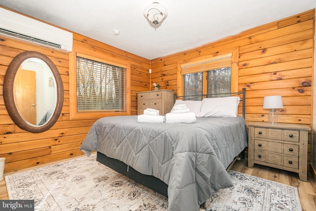 bedroom with a wall mounted AC, wood finished floors, and wooden walls