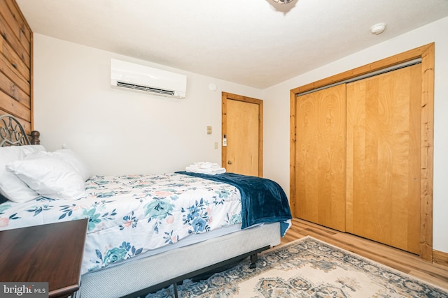 bedroom with a wall unit AC, a closet, and wood finished floors