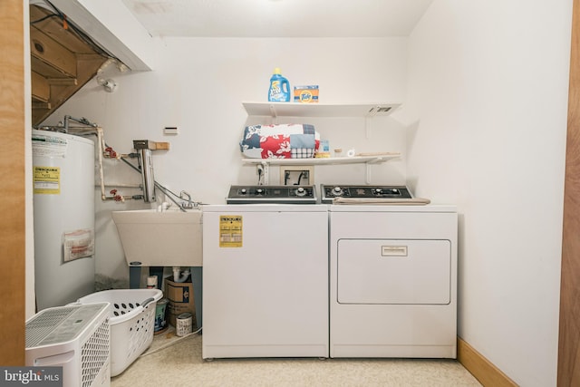 clothes washing area with gas water heater, independent washer and dryer, a sink, and laundry area