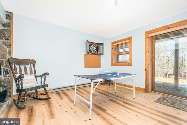 recreation room with baseboard heating, wood finished floors, and baseboards