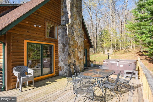 deck with outdoor dining space and a hot tub