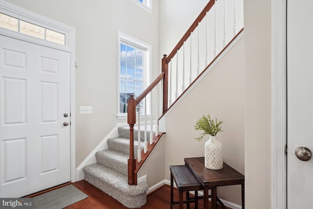 entrance foyer with stairway, dark wood-style flooring, and baseboards