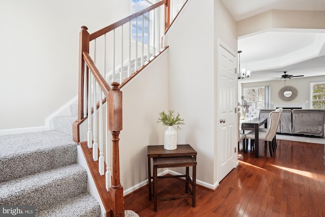 stairs featuring ceiling fan with notable chandelier, a fireplace, baseboards, and hardwood / wood-style flooring