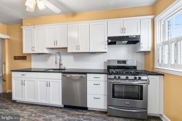 kitchen featuring dark countertops, appliances with stainless steel finishes, under cabinet range hood, and a sink