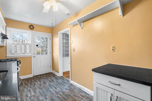 doorway with baseboards and ceiling fan