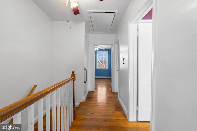 hall featuring wood finished floors, attic access, an upstairs landing, and baseboards