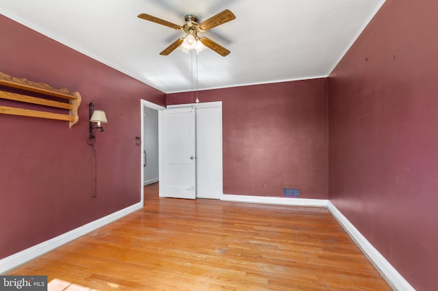 unfurnished bedroom with a closet, ceiling fan, baseboards, and wood finished floors