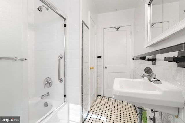 bathroom featuring tile patterned flooring, tile walls, washtub / shower combination, and a sink