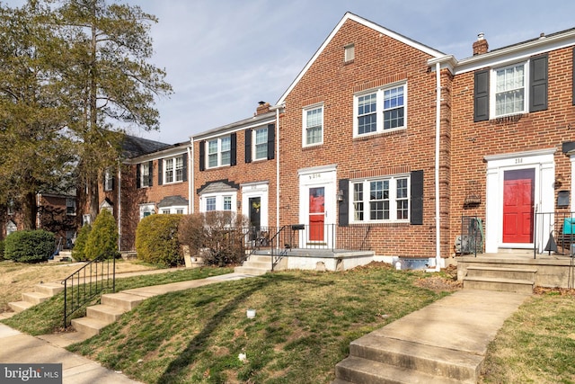 view of property featuring brick siding and a front yard