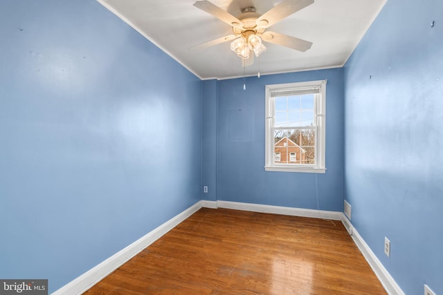 spare room with ceiling fan, ornamental molding, baseboards, and wood finished floors