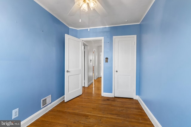 unfurnished bedroom featuring ornamental molding, wood finished floors, visible vents, and baseboards