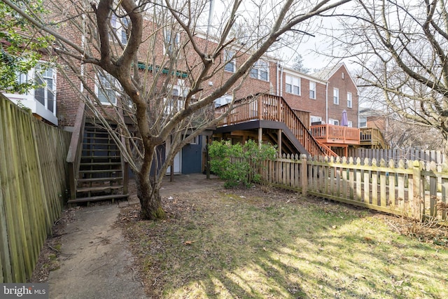 view of yard with stairs, a deck, and a fenced backyard