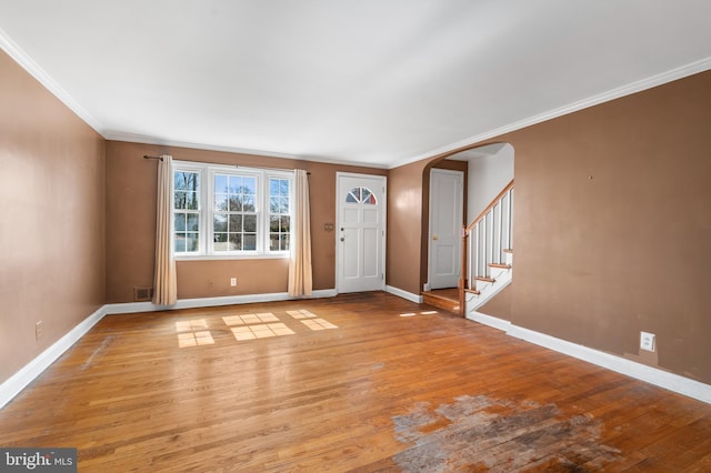 foyer featuring arched walkways, baseboards, stairs, and light wood-style floors