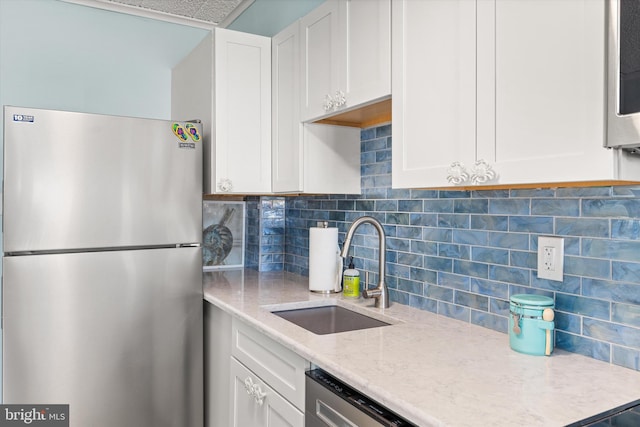 kitchen with white cabinets, decorative backsplash, stainless steel appliances, and a sink