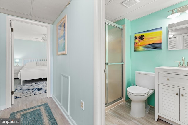 ensuite bathroom with a stall shower, visible vents, and wood finished floors