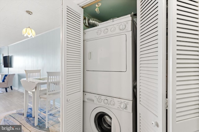 laundry room featuring laundry area, wood finished floors, and stacked washer / drying machine