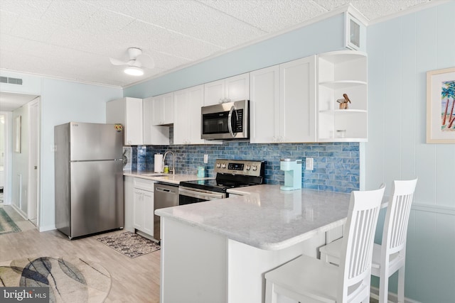 kitchen with open shelves, stainless steel appliances, tasteful backsplash, light wood-style floors, and a sink