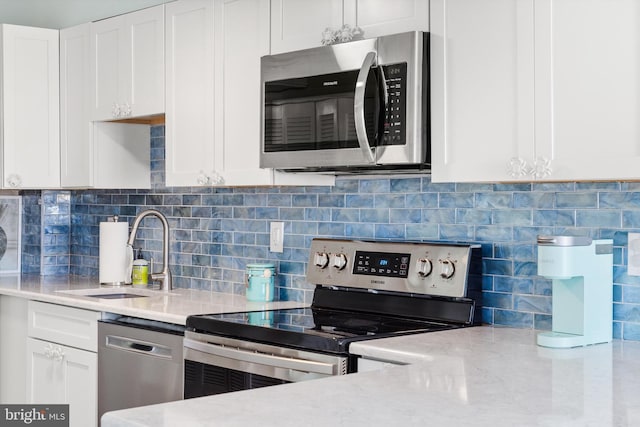 kitchen featuring white cabinets, tasteful backsplash, stainless steel appliances, and a sink