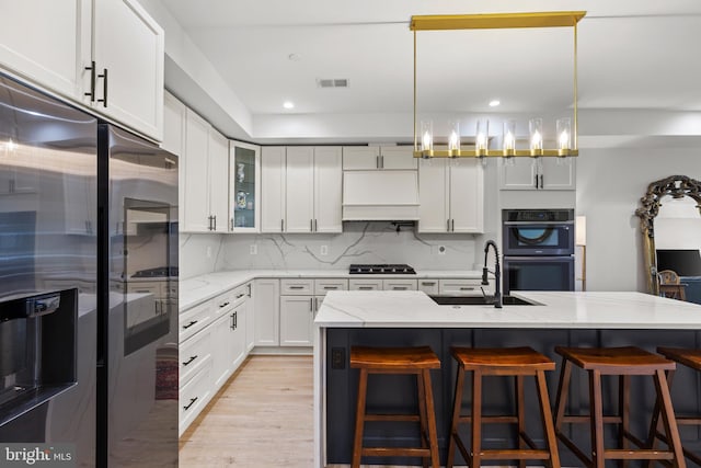 kitchen featuring double wall oven, a sink, tasteful backsplash, gas stovetop, and stainless steel fridge