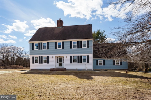 view of front of house with entry steps, a chimney, and a front lawn