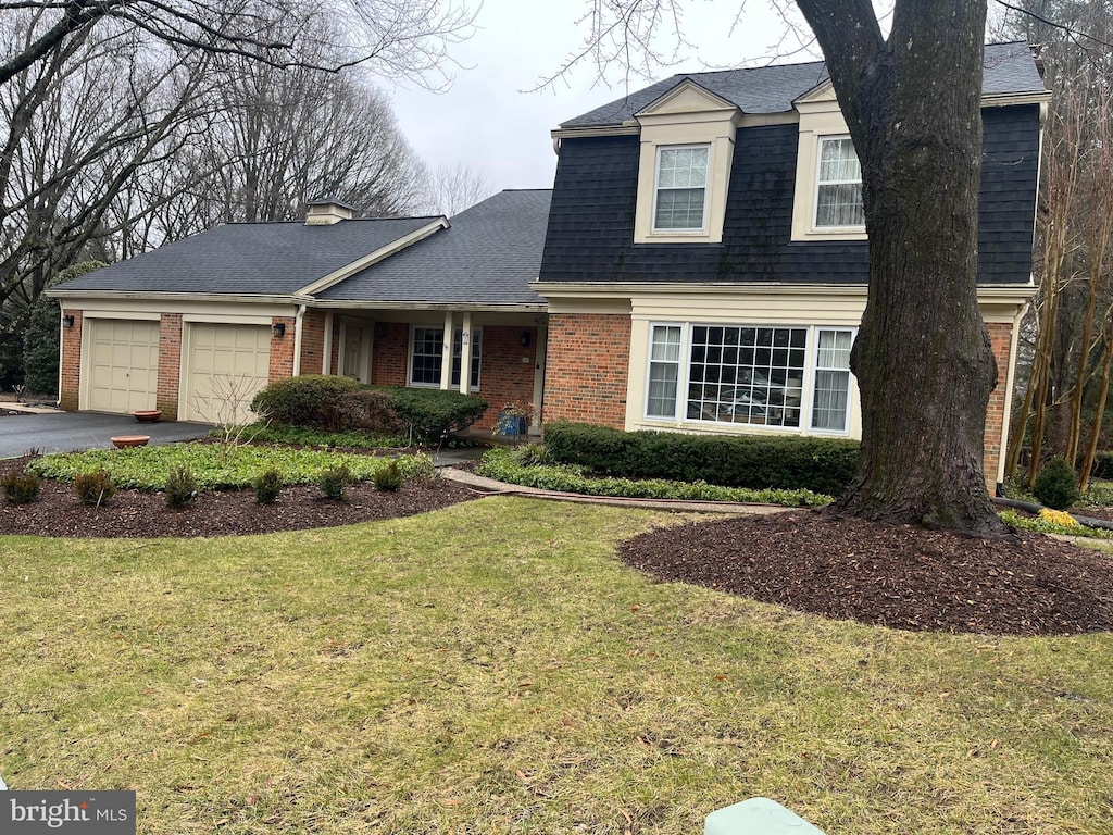 dutch colonial with a front lawn, aphalt driveway, an attached garage, a shingled roof, and brick siding