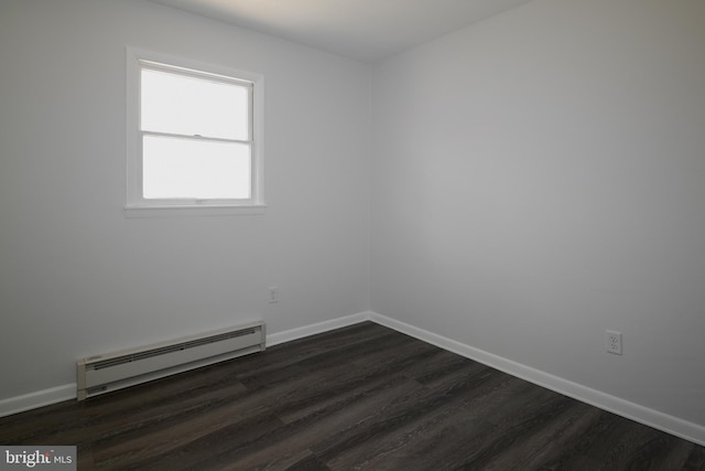 empty room with a baseboard heating unit, dark wood finished floors, and baseboards