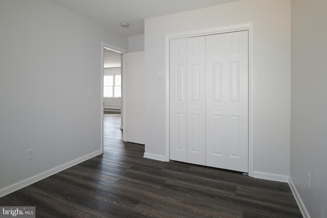 unfurnished bedroom featuring a closet, dark wood finished floors, and baseboards