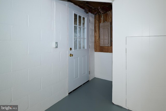 interior space with concrete block wall, electric panel, and concrete floors