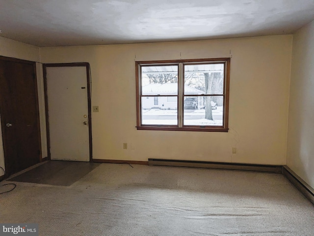 spare room featuring a baseboard heating unit, carpet flooring, and baseboards