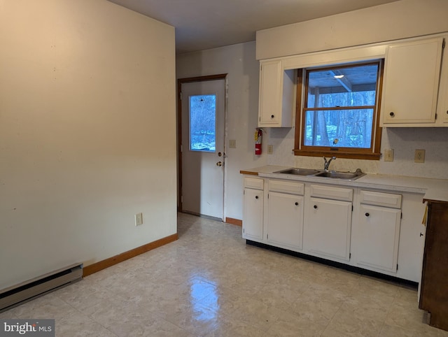 kitchen featuring light countertops, a baseboard heating unit, white cabinetry, a sink, and baseboards