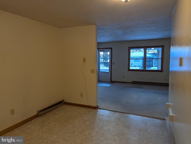 spare room with light carpet, baseboard heating, and baseboards