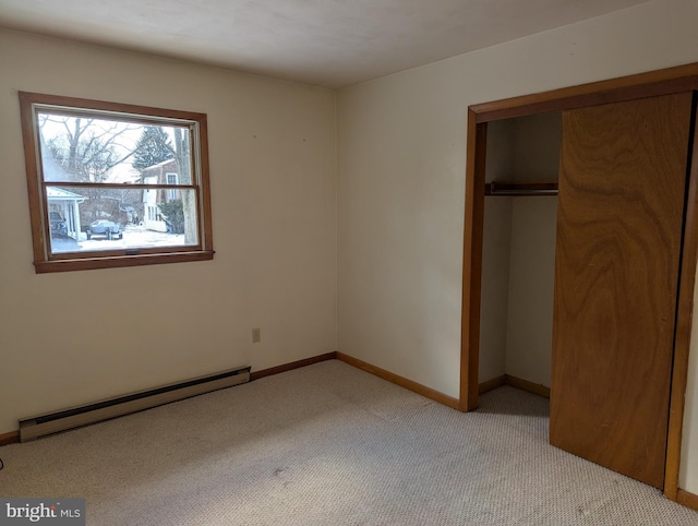 unfurnished bedroom featuring light carpet, baseboard heating, a closet, and baseboards