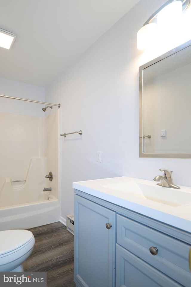 bathroom with toilet, wood finished floors, vanity, shower / washtub combination, and baseboard heating