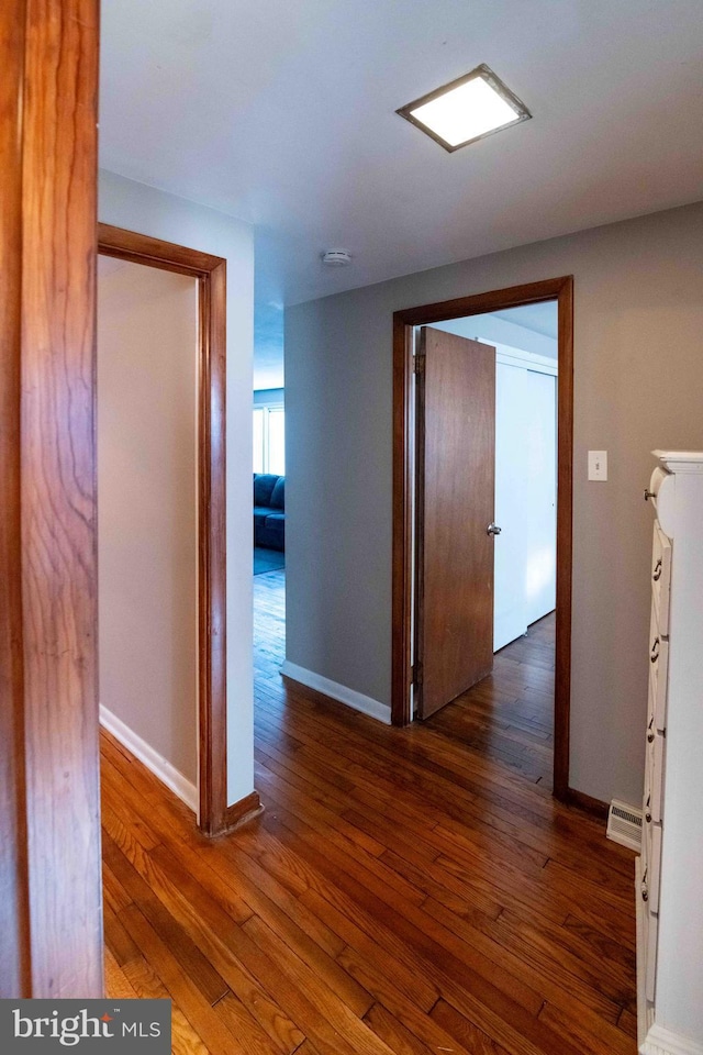 corridor with visible vents, baseboards, and wood-type flooring