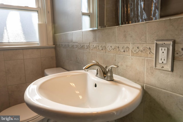 half bathroom featuring a wealth of natural light, toilet, and a sink