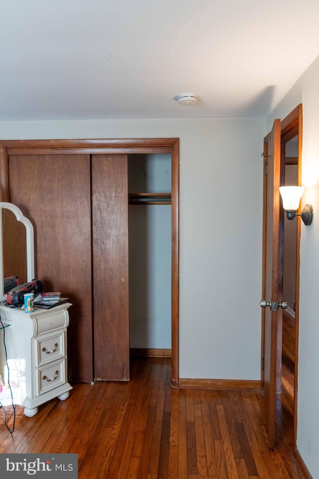 unfurnished bedroom featuring a closet, baseboards, and hardwood / wood-style flooring