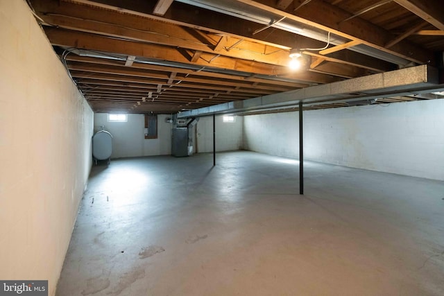 basement with electric panel, heating unit, and heating fuel