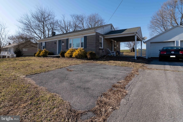 view of front of home featuring driveway, an outbuilding, and a front lawn