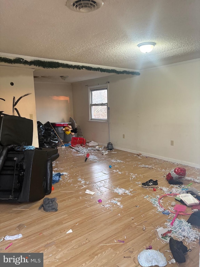 interior space with a textured ceiling, hardwood / wood-style floors, visible vents, and baseboards