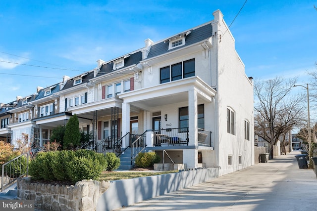 view of front of home with mansard roof, a residential view, and brick siding