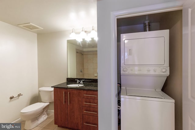 full bathroom featuring tile patterned flooring, toilet, stacked washer / dryer, visible vents, and vanity