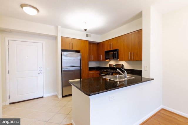 kitchen with appliances with stainless steel finishes, visible vents, brown cabinets, and a peninsula