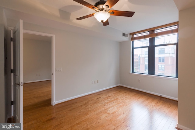 spare room with ceiling fan, light wood finished floors, visible vents, and baseboards