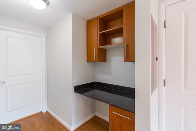 interior space featuring light wood finished floors, baseboards, and built in desk