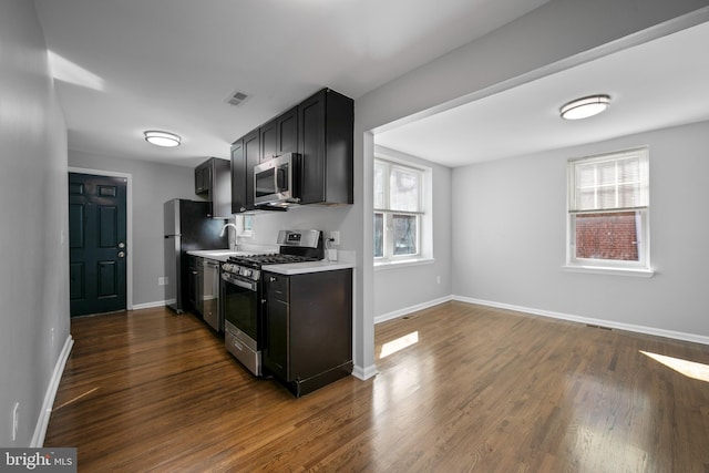 kitchen with baseboards, visible vents, appliances with stainless steel finishes, dark wood-style flooring, and light countertops