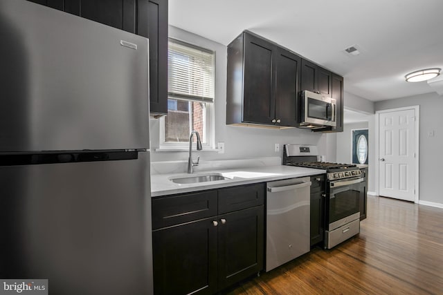 kitchen with baseboards, visible vents, dark wood-type flooring, stainless steel appliances, and a sink